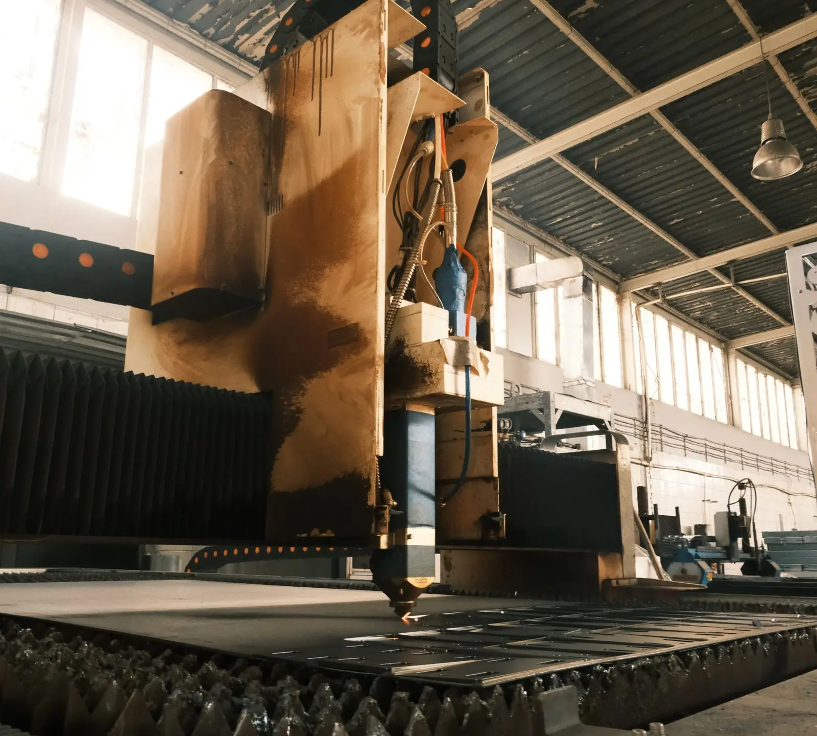 An industrial laser machine cutting steel plate on a factory floor
