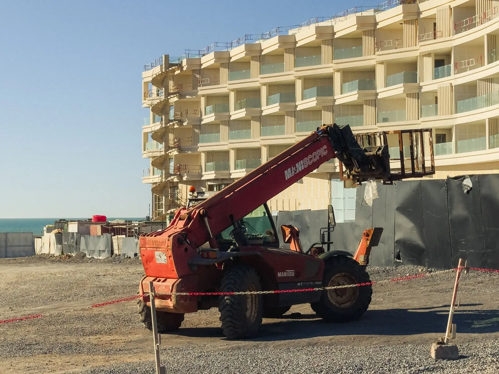 A telehandler working in front of a new apartment block